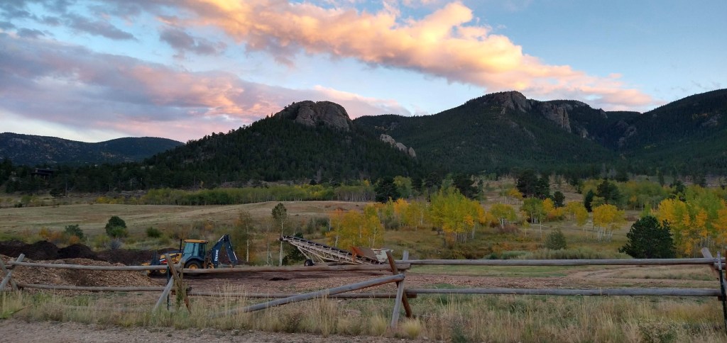 Mountains and clouds with yellow aspen and Deere equipment