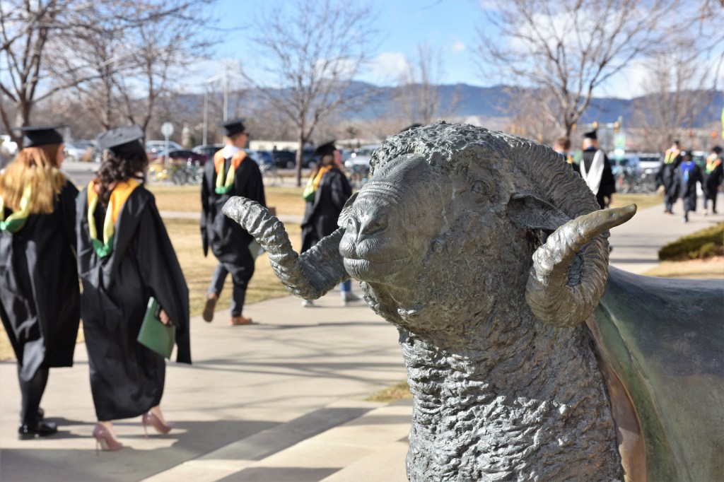 Ram sculpture with graduating students walking by outside