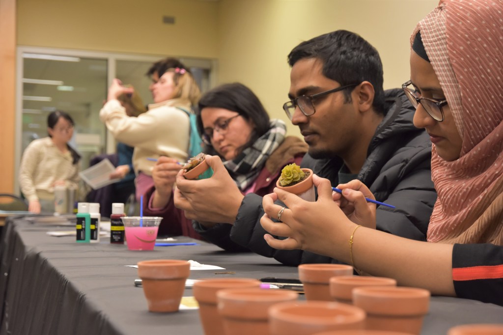 Graduate students painting small succulent pots